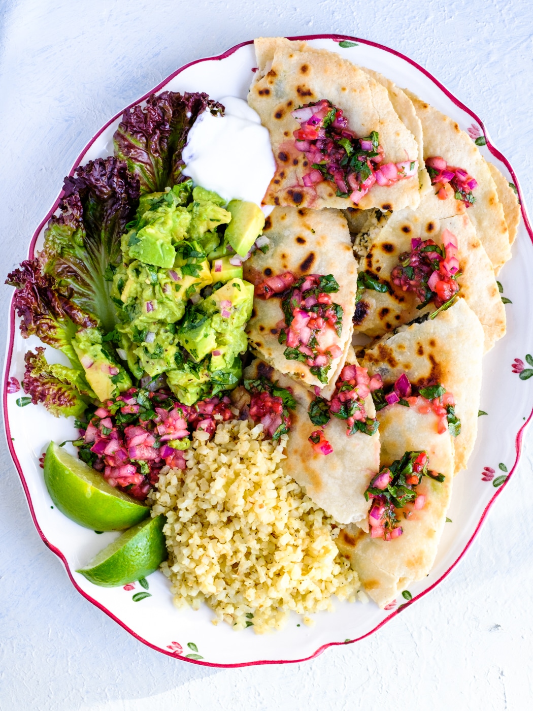 The chicken quesadillas on a plate served with chunky guacamole, cauliflower rice and salsa