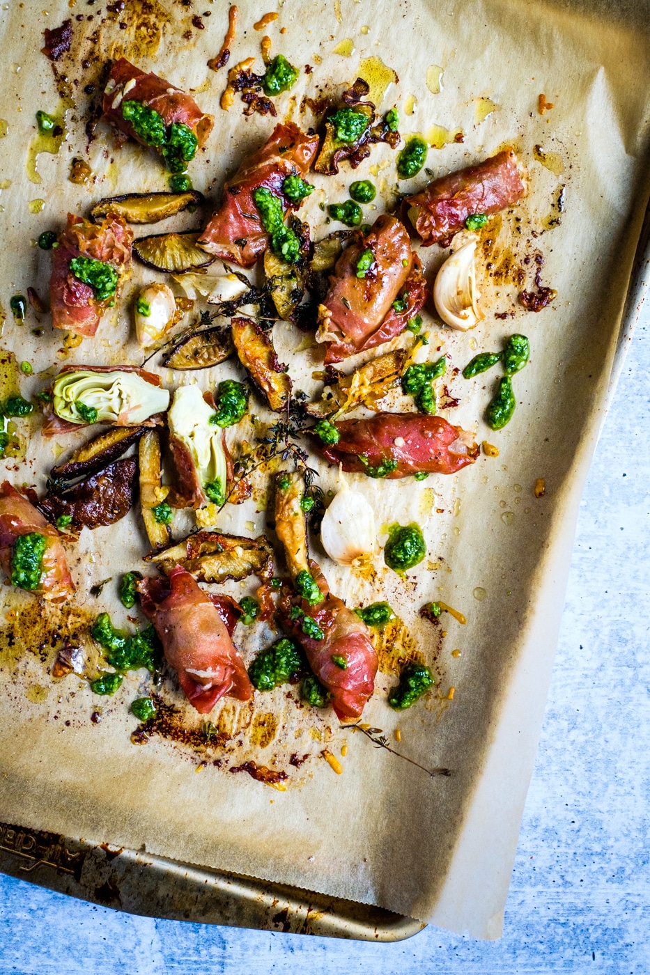 Baked prosciutto wrapped artichoke hearts on a baking sheet