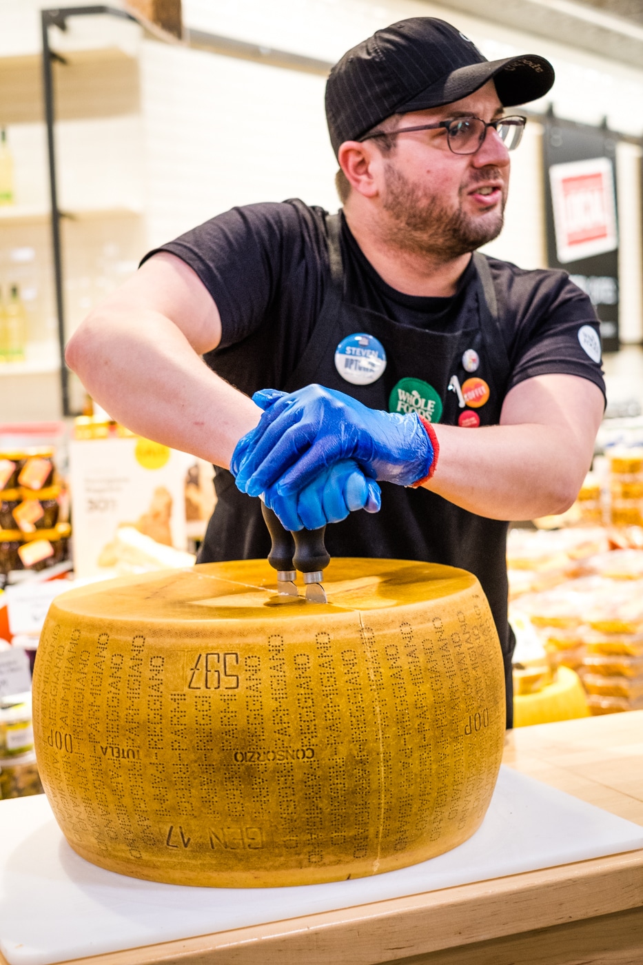 Closeup of a man slicing a Parmigiano Reggiano cheese wheel Stock