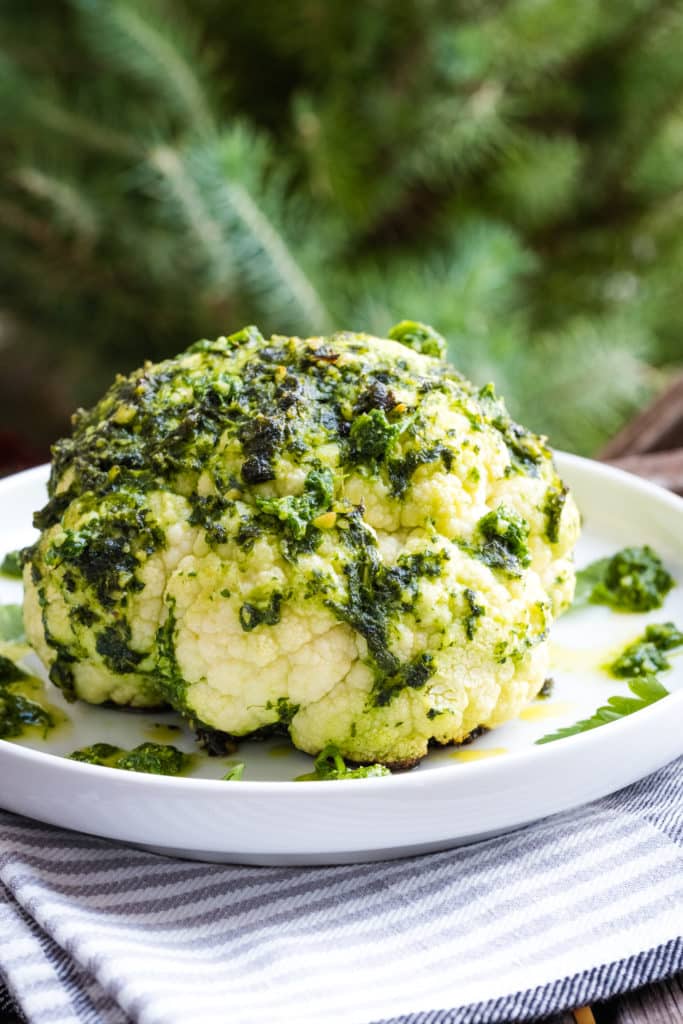 Whole roasted cauliflower with pesto served on a plate