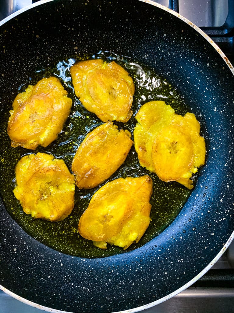 Frying the sliced green plantains in a pan