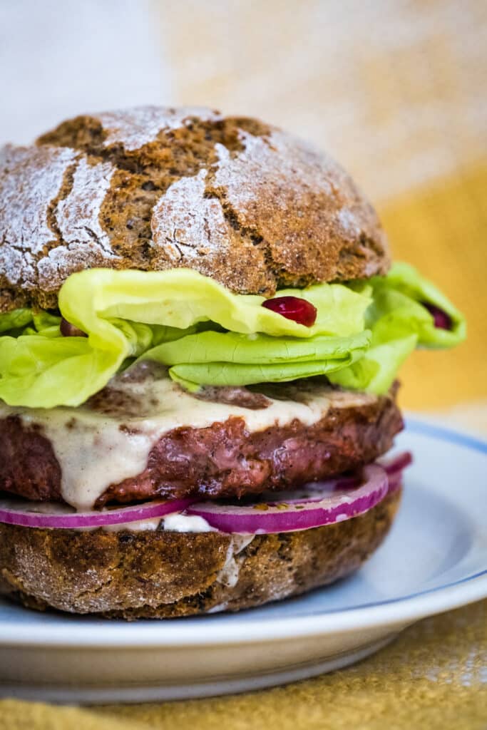 A lectin-free, gluten-free burger with grass-fed beef pattie, salad, onions and tahini sauce