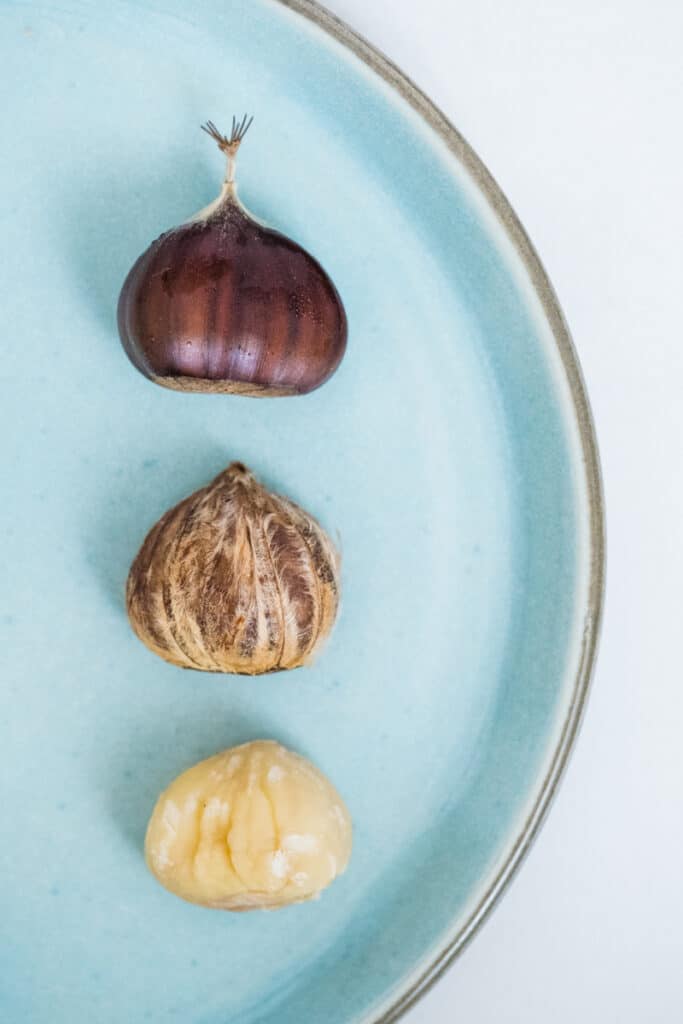 Peeling a chestnut. The brown and shiny one is the outer shell.