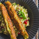 2 chicken kofta kebabs on top of millet tabbouleh, in a black plate