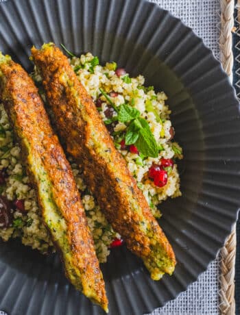 2 chicken kofta kebabs on top of millet tabbouleh, in a black plate