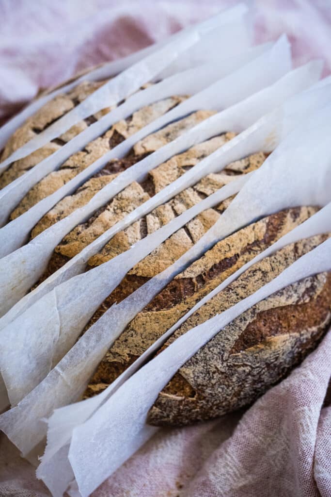 The sliced gluten free sourdough bread. The slices are separated with parchment paper, which makes it easier to freeze them.