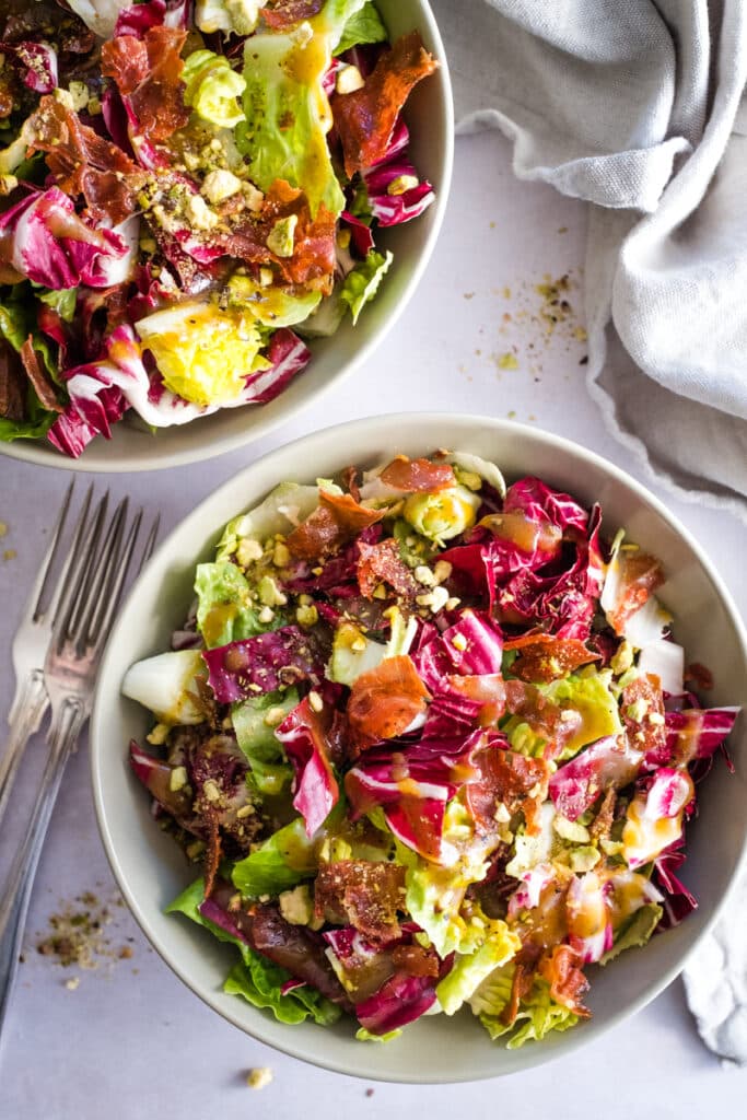 Two bowls with bistro salad and crispy prosciutto