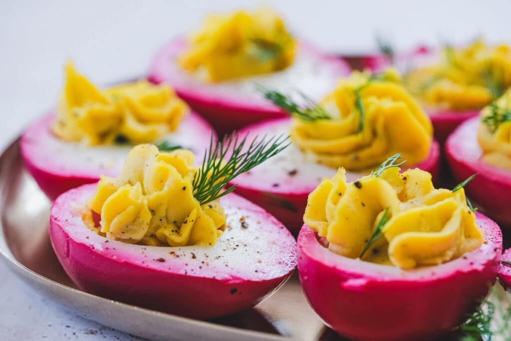 Beet-pickled deviled eggs arranged on a serving platter.