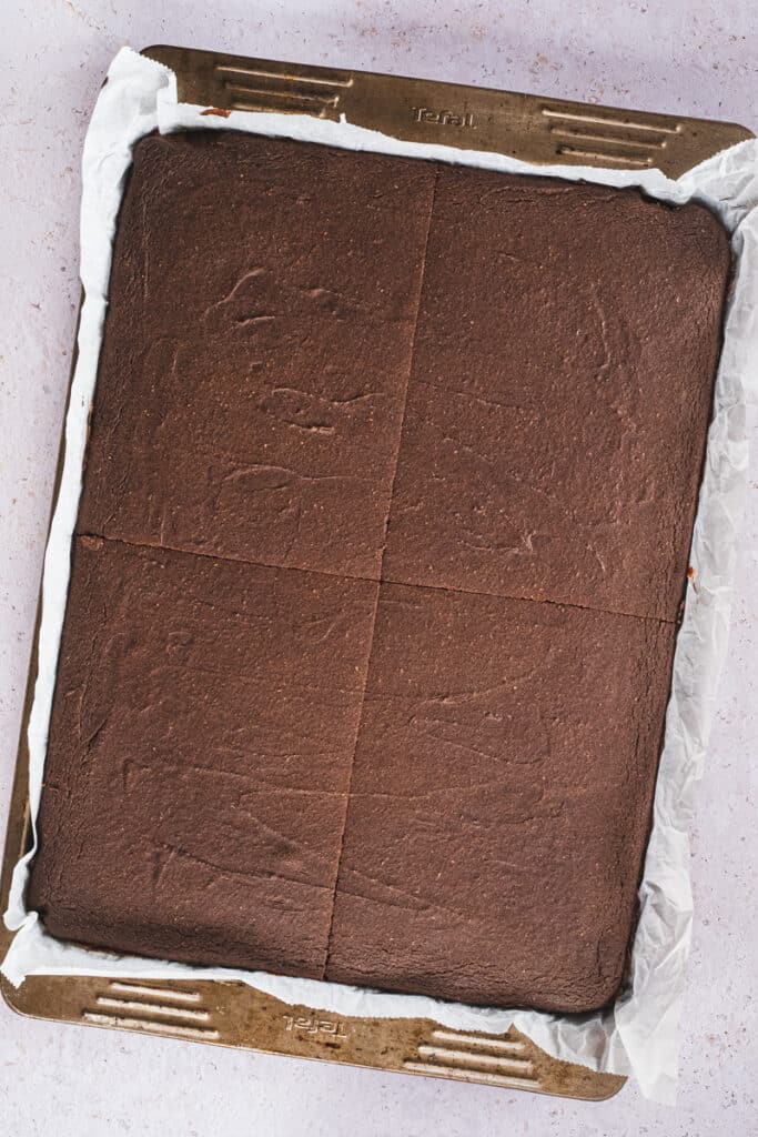 The gluten-free sheet cake has cooled and been cut into four rectangular pieces.