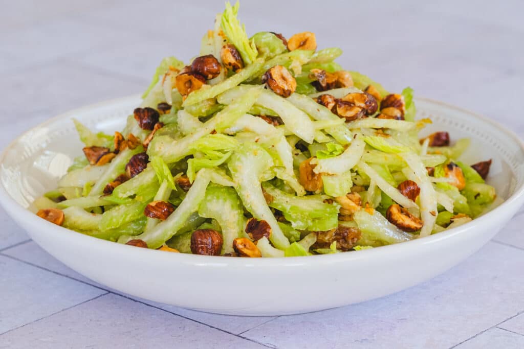 Celery salad with parmesan and toasted hazelnuts served in a bowl