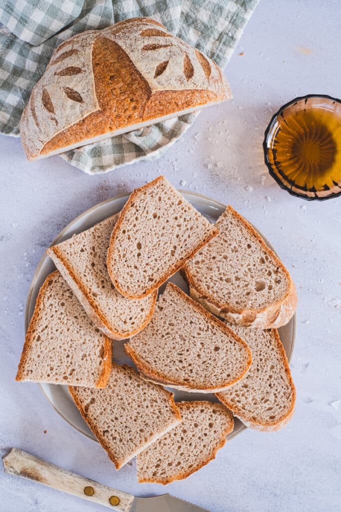 sorghum sourdough bread slices on a plate and half a bread