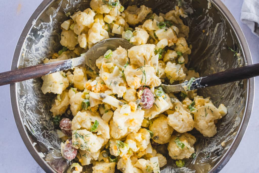 The cauliflower salad has been thoroughly mixed in a bowl.