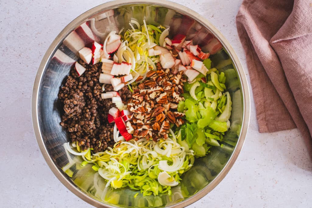 The ingredients for the black lentil salad are in a mixing bowl and ready to be tossed.