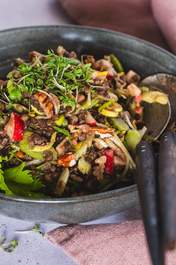 Black lentil salad with celery, apple, and toasted pecans in a serving bowl.