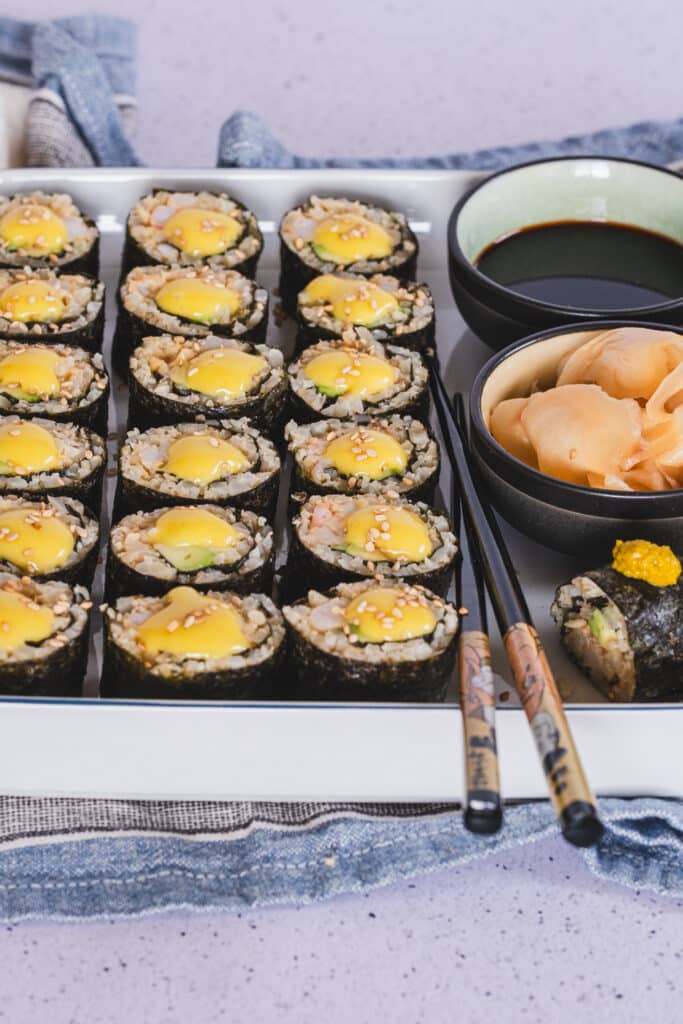 Low carb sushi rolls topped with spicy mayonnaise, served with coconut aminos and pickled ginger. All served on a plate.