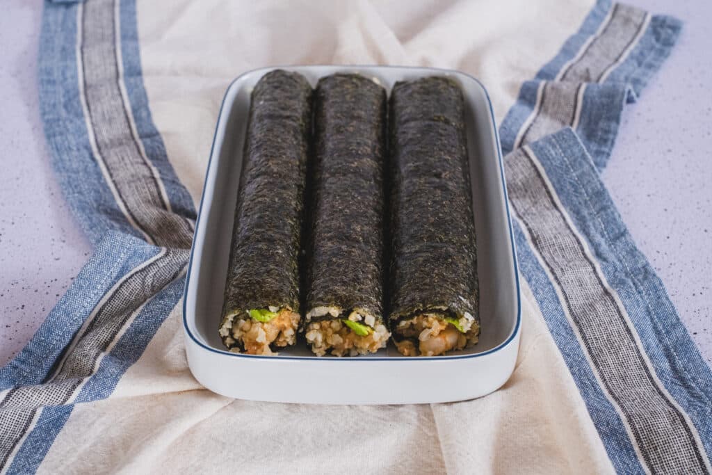 The three low-carb sushi rolls with cauliflower rice are ready to be sliced.