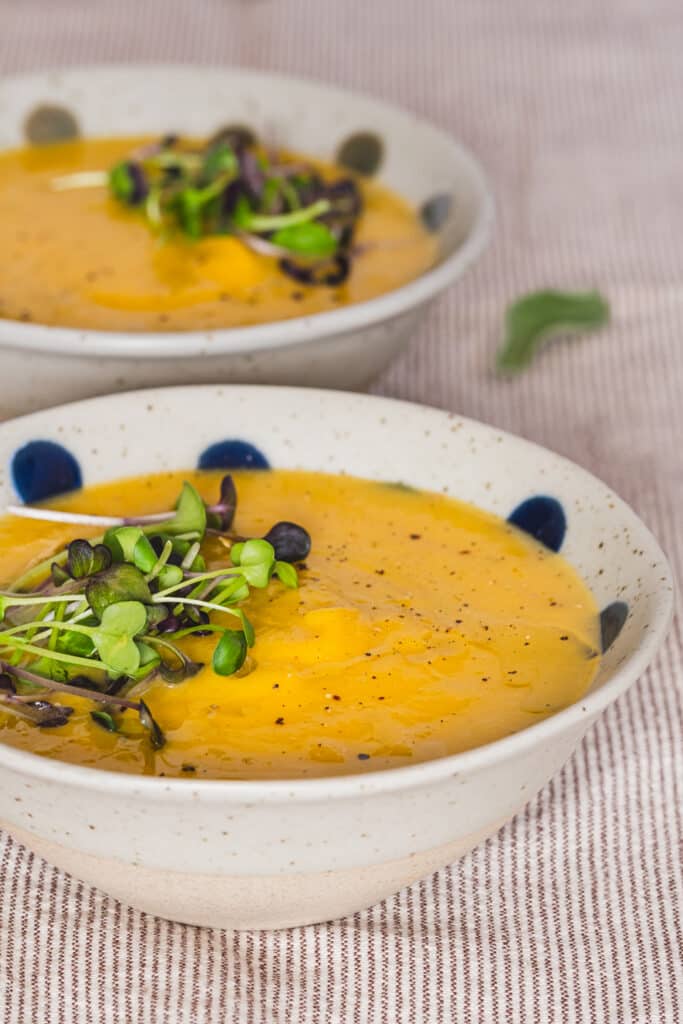 Creamy butternut squash soup served in a bowl and garnished with microgreens.