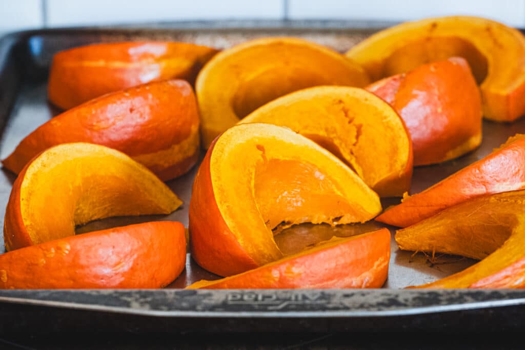 Slices of pumpkin arranged on a baking sheet.