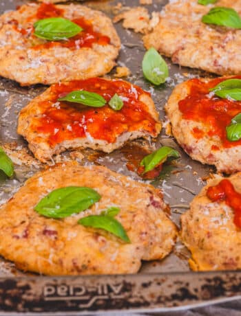 cottage cheese pizza bites on a baking sheet, topped with ketchup and basil leaves