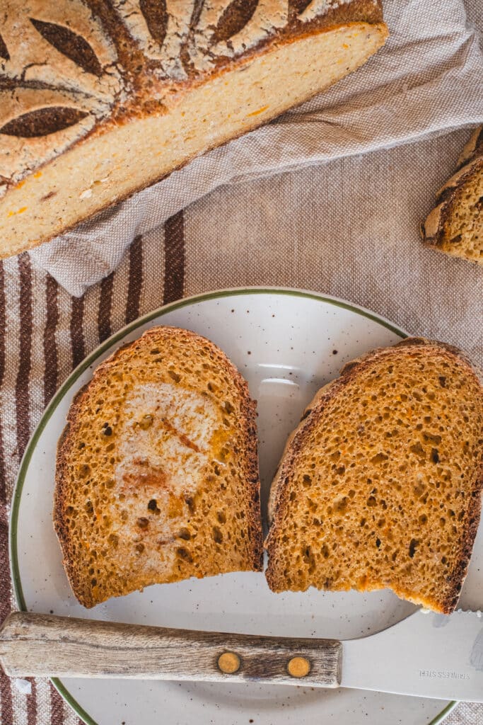 Toasted bread slices. One of the slices is spread with butter.