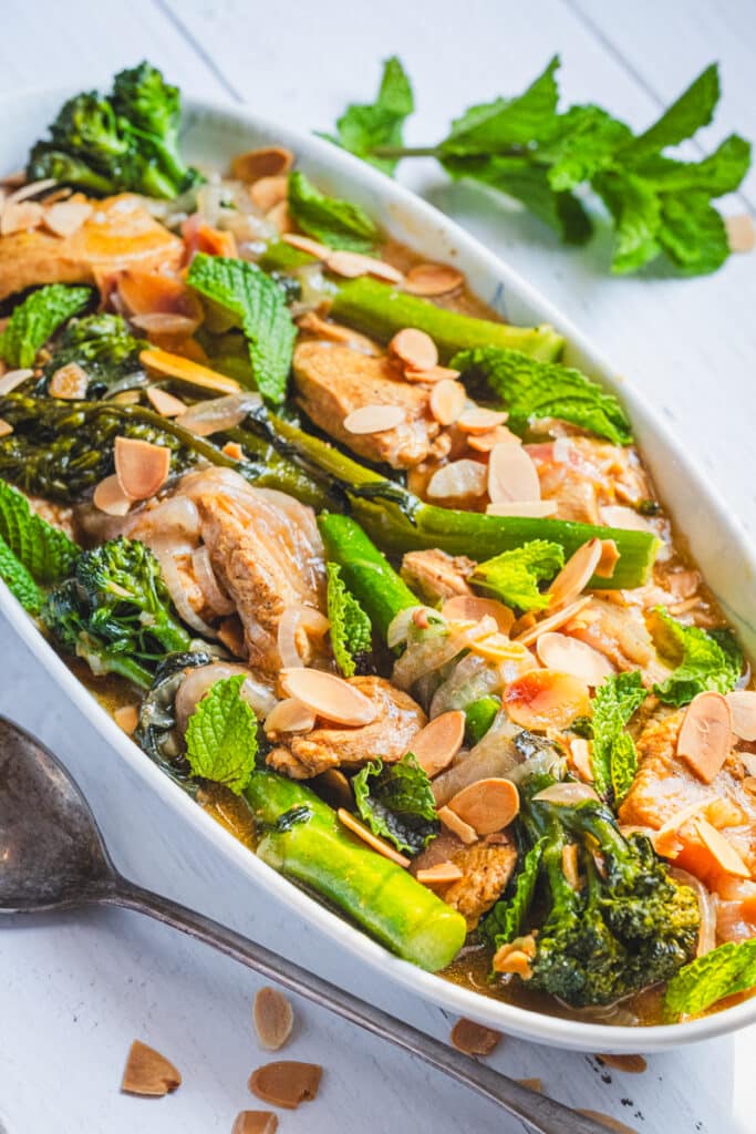 moroccan chicken with broccolini and almonds on a serving platter