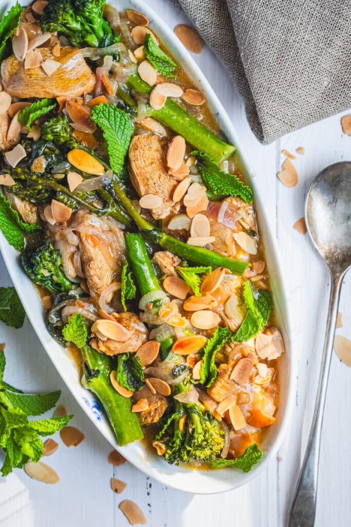 moroccan chicken with broccolini and almonds on a serving platter