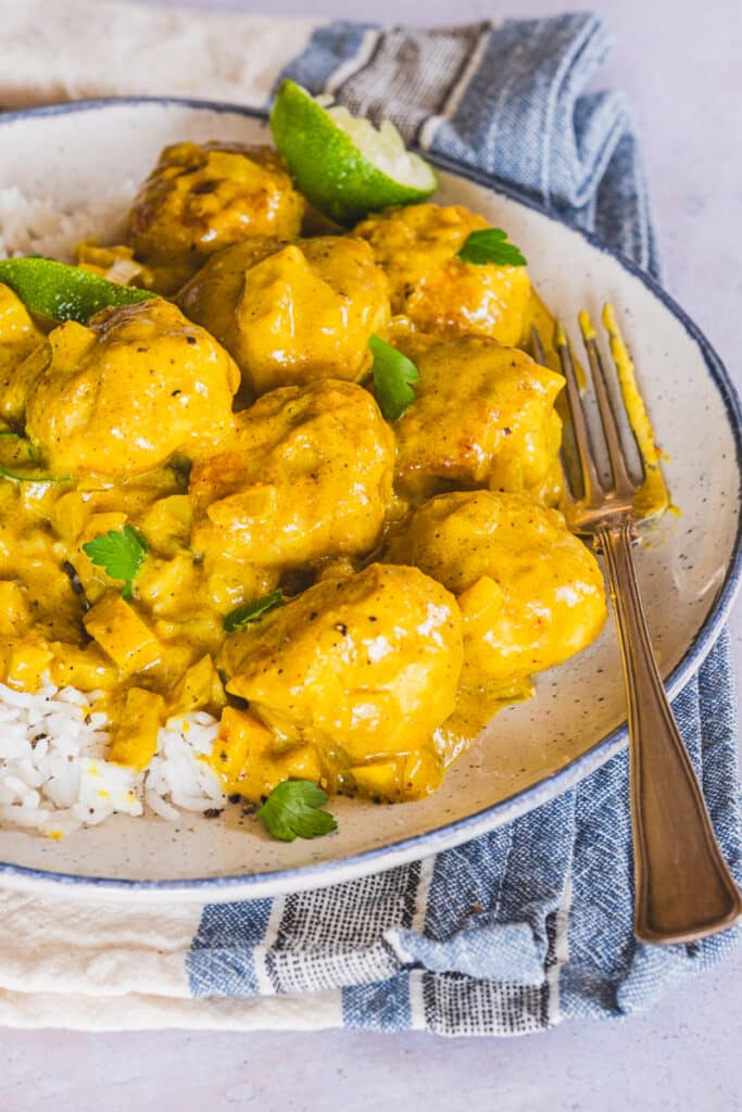 The coconut curry chicken meatballs served with rice on a plate.