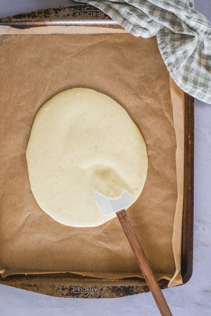Spreading the flatbread mixture evenly onto a baking sheet lined with parchment paper.