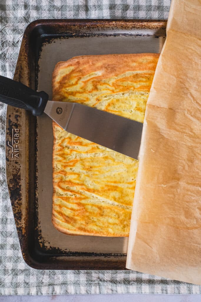 Gently using a spatula to remove the parchment paper from the flatbread.