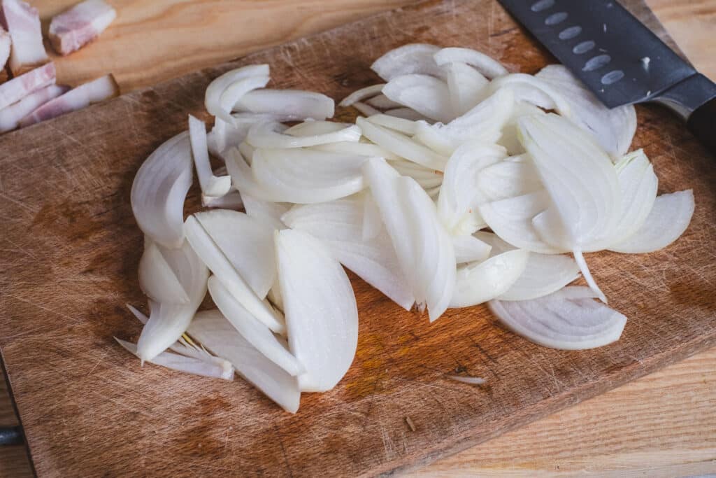 Thinly sliced onions on a cutting board.