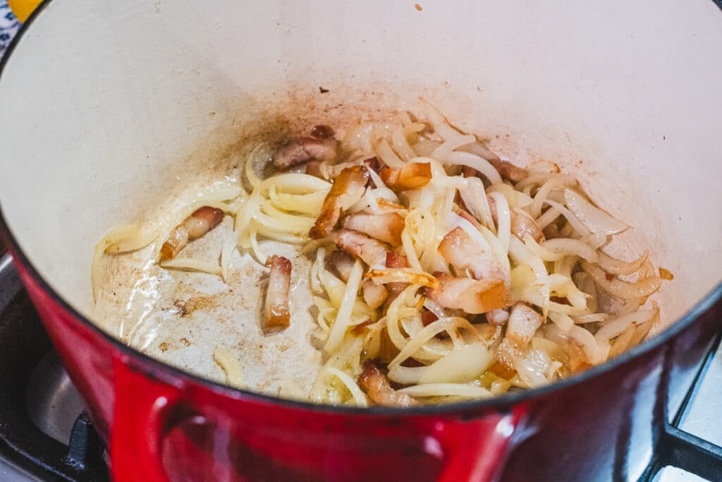 Diced bacon and onions are cooking in large pot.