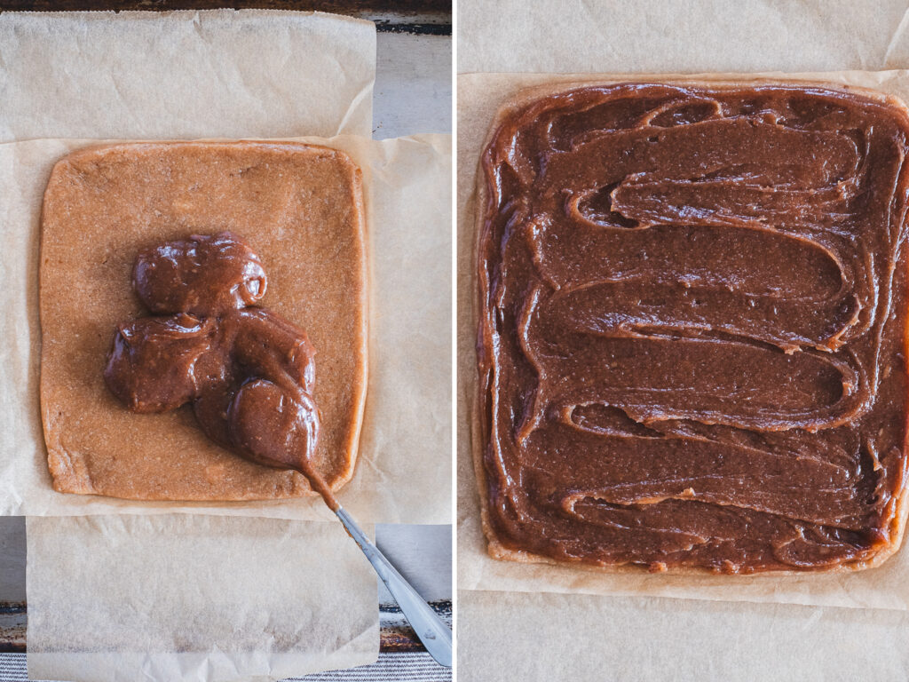 Spreading golden caramel evenly over the base layer on parchment paper.