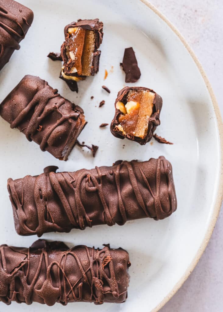 Healthy Snickers bars neatly arranged on a white ceramic plate.