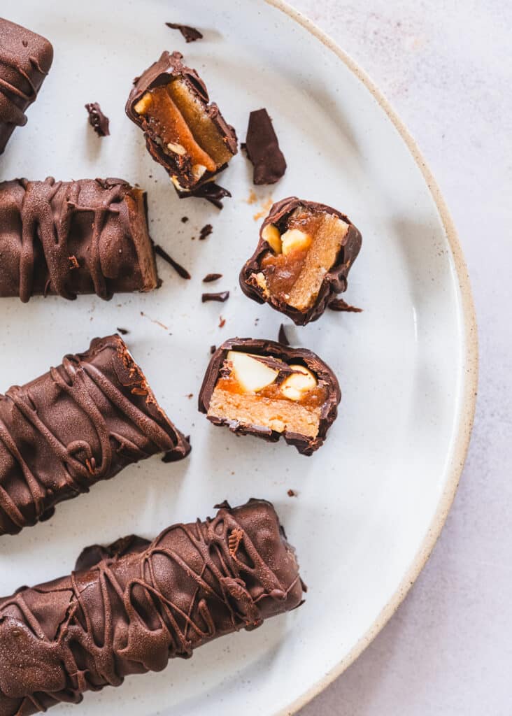 Snickers bars neatly arranged on a white ceramic plate.