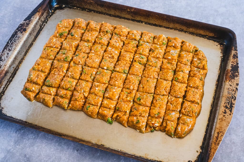 A baking sheet displays the chicken mixture spread evenly and shaped into neat rectangular portions, ready to go into the oven.