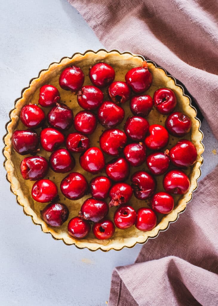 a partially prebaked tart crust with pitted cherries