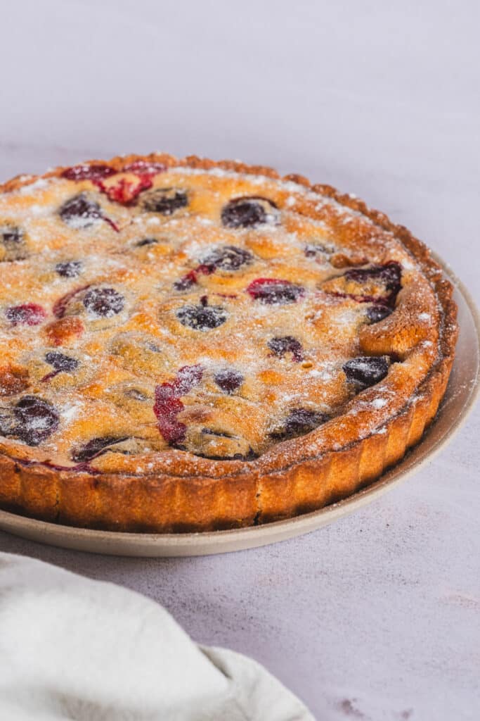 Gluten free plum tart, dusted with allulose, on a serving platter