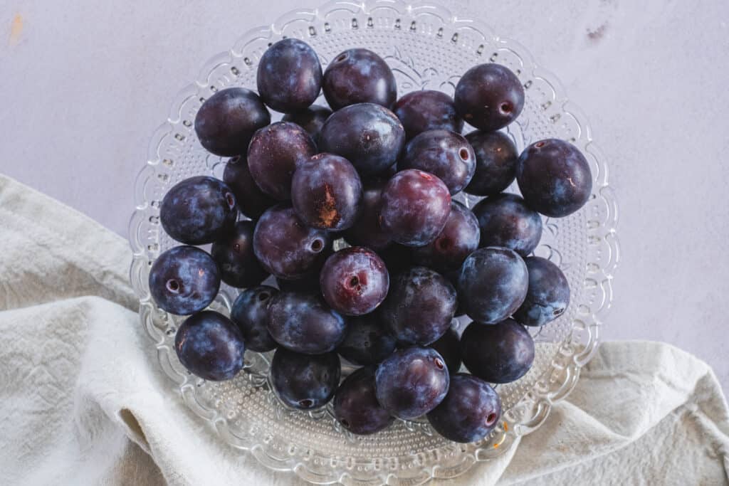 A glass plate with fresh plums.