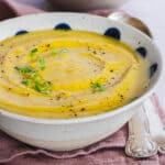 creamy red lentil and cauliflower soup served in a bowl, topped with broccoli microgreens