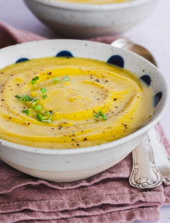creamy red lentil and cauliflower soup served in a bowl, topped with broccoli microgreens