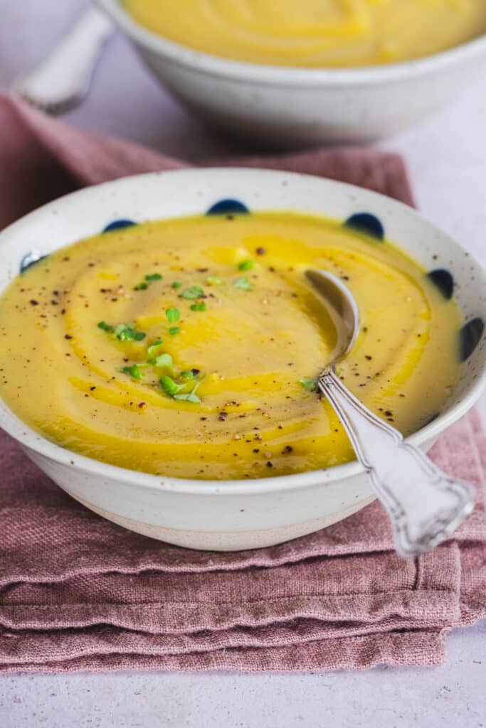 lentil and cauliflower soup, topped with broccoli microgreens, served in a bowl, with a spoon