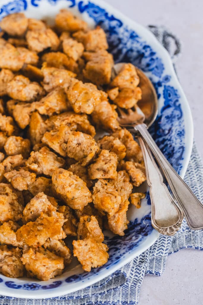 Homemade Italian chicken sausage bites on a platter with blue edges, served with a fork and spoon