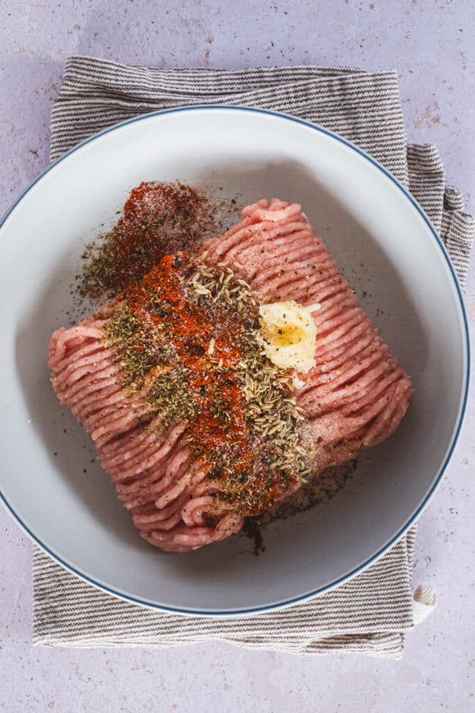 ground chicken, spices, and pressed garlic in a bowl
