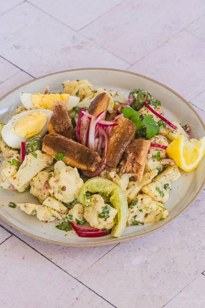 Sardine and cauliflower salad in a white plate.